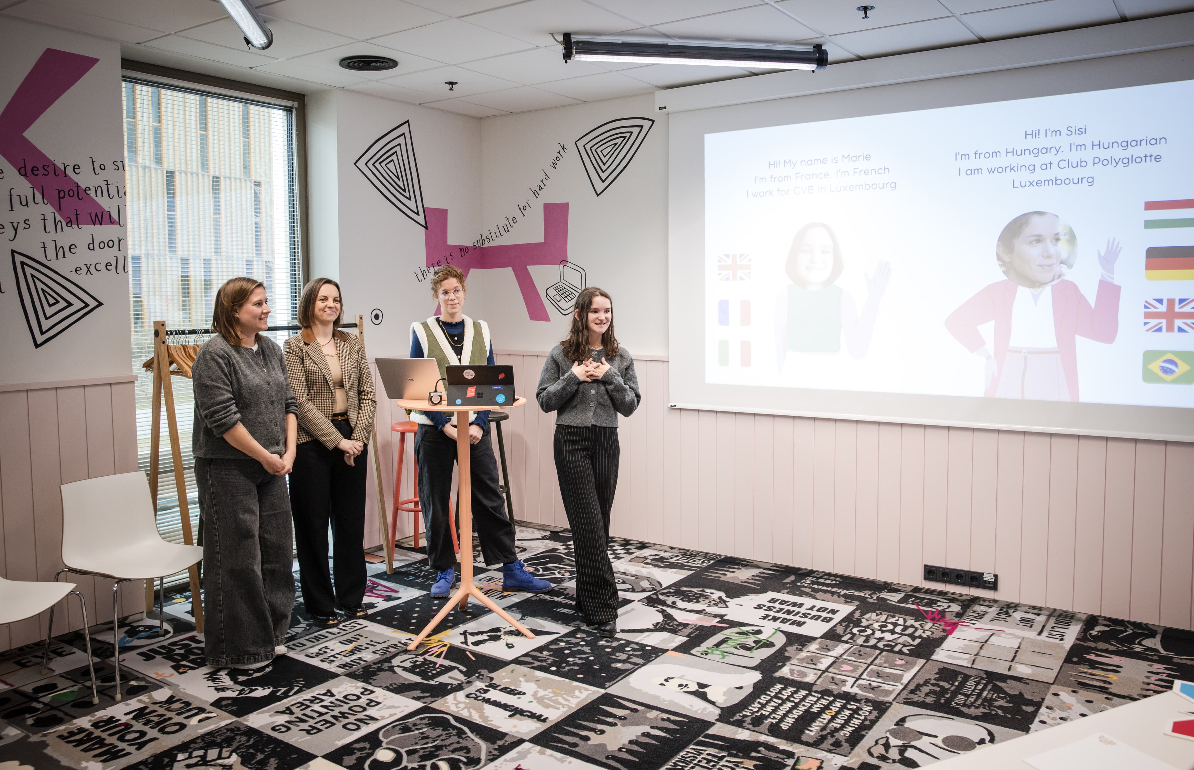 Four women present beside a projected introduction slide in a colourful workshop room